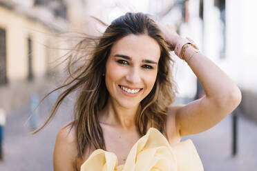Happy young woman with hand in hair - DAMF01082
