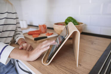 Woman using tablet PC on kitchen counter at home - EBBF05885