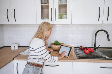 Junge Frau benutzt Tablet-PC auf dem Küchentisch zu Hause - EBBF05887