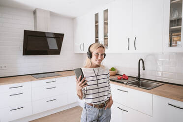 Woman with smart phone listening music through smart phone at home - EBBF05901