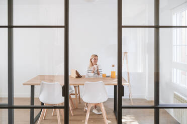 Thoughtful young woman with coffee cup at home - EBBF05905