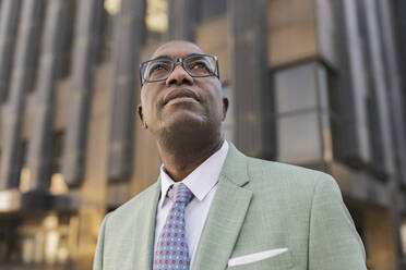 Mature businessman standing in front of building - JCCMF07090