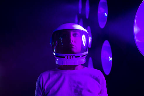 Astronaut mit Weltraumhelm vor beleuchteter Kulisse - MEUF07837