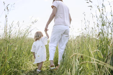 Mother with daughter walking amidst plants on field - EYAF02022