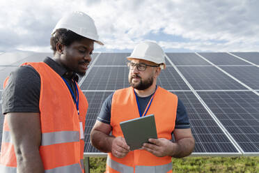 Engineer and co workers with tablet PC discussing at solar station - OSF00627