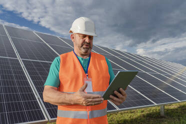 Engineer standing with tablet PC at solar station - OSF00630