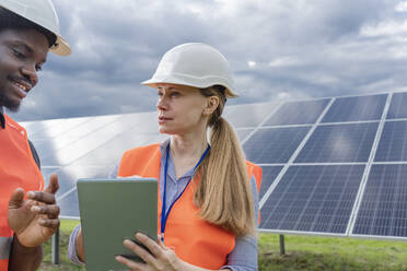 Engineers discussing over tablet PC in front of solar panels - OSF00635