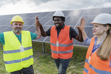 Lächelnde, gemischtrassige Ingenieure geben sich im Solarkraftwerk gegenseitig High Five - OSF00662