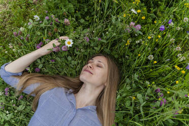 Smiling woman with eyes closed lying on grass at field - OSF00669