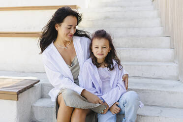 Smiling woman with daughter sitting on steps - SEAF01169