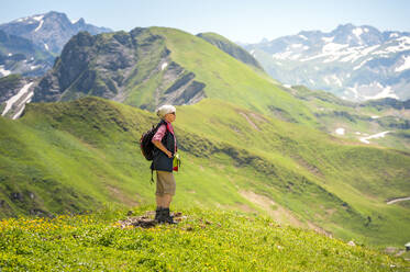 Senior woman standing on mountain looking into valley, Mountain Nebelhorn, Allgau, Bavaria, Germany - FRF00958