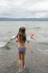 Rückenansicht Mädchen auf dem Meer Ufer Spaß an einem bewölkten Tag - ADSF36206