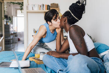 Lesbisches Paar küsst sich auf dem Bett zu Hause - MEUF07870