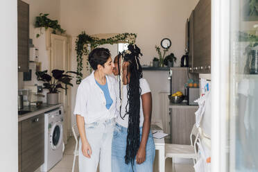 Lesbisches Paar küsst sich in der Küche zu Hause - MEUF07912