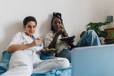 Lesbisches Paar, das zu Hause auf dem Laptop einen Film ansieht - MEUF07921
