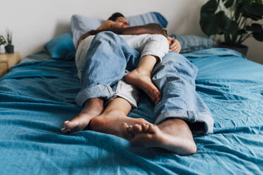 Lesbisches Paar, das sich gegenseitig umarmt, indem es zu Hause auf dem Bett liegt - MEUF07939
