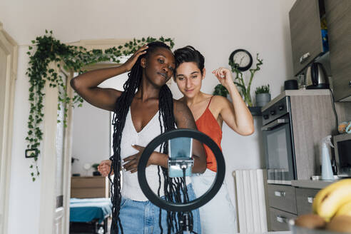 Lesbisches Paar, das zu Hause mit dem Smartphone auf dem Klingelschild filmt - MEUF07943