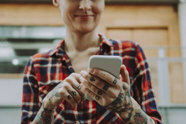 Smiling woman with tattoo using smart phone - OIPF02310