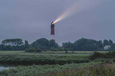 Deutschland, Schleswig-Holstein, Pellworm, Pellwormer Leuchtturm wirft buntes Licht in der Dämmerung - KEBF02394