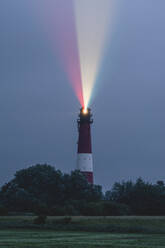 Germany, Schleswig-Holstein, Pellworm, Pellworm Lighthouse casting colorful light at dusk - KEBF02396