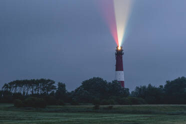 Germany, Schleswig-Holstein, Pellworm, Pellworm Lighthouse casting colorful light at dusk - KEBF02397