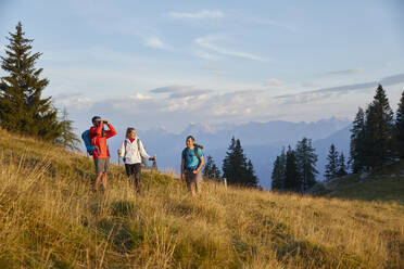 Mann schaut durch ein Fernglas und steht mit Freunden auf einem Berg, Mutters, Tirol, Österreich - CVF02162