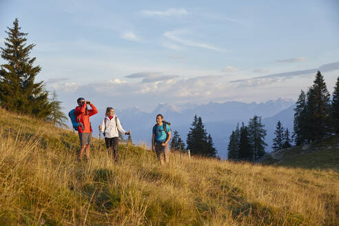 Mann schaut durch ein Fernglas und steht mit Freunden auf einem Berg, Mutters, Tirol, Österreich - CVF02162