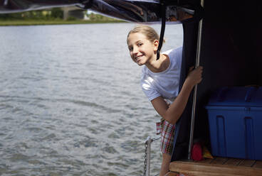 Lächelndes Mädchen, das auf dem Bootsdeck im Urlaub steht - RHF02595