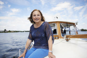 Smiling senior woman sitting on boat deck - RHF02619