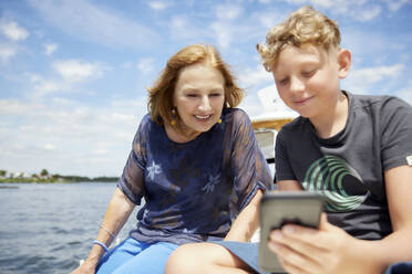 Junge teilt Smartphone mit Großmutter auf Boot - RHF02622