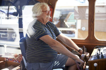 Senior man holding helm sailing motorboat on vacation - RHF02646