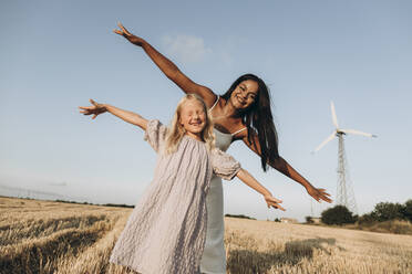 Cheerful woman and girl with arms outstretched at farm - SIF00349