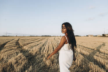 Petite woman walking in the grain field, wearing white dress