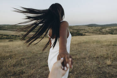 Frau mit zerzaustem Haar hält Hand eines Mädchens auf einer Wiese - SIF00361