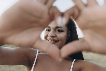 Smiling woman making heart shape with hand - SIF00368