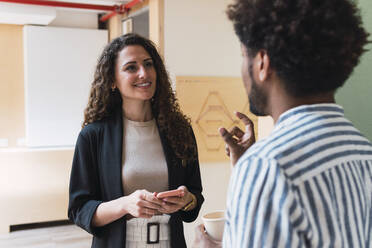 Male and female colleague talking in office - PNAF04326