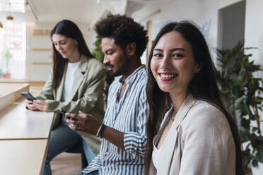 Portrait of smiling businesswoman with colleagues in office - PNAF04380