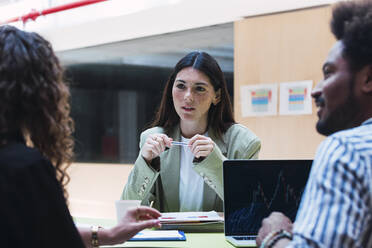 Businesswoman listening to colleague during a meeting in office - PNAF04424