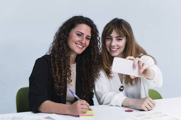 Two happy businesswomen taking a selfie in office - PNAF04440