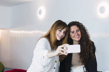 Zwei glückliche Geschäftsfrauen machen ein Selfie im Büro - PNAF04445