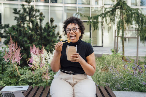 Happy businesswoman having lunch sitting on bench - VPIF06973