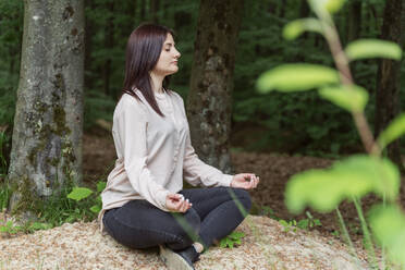 Young woman meditating in forest - OSF00697