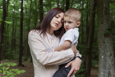 Mutter mit geschlossenen Augen trägt Sohn im Wald - OSF00699
