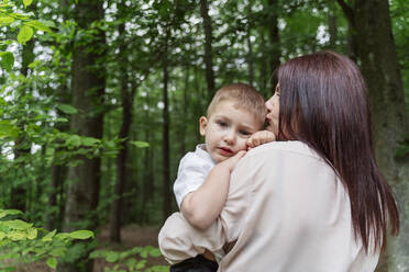 Mother kissing son in forest - OSF00700
