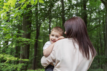 Mother carrying smiling son in forest - OSF00701