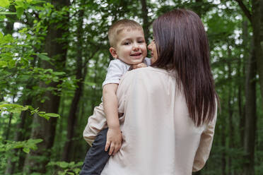 Happy son with mother amidst trees in forest - OSF00702