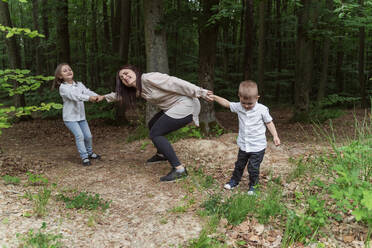 Children pulling mother having fun in forest - OSF00707