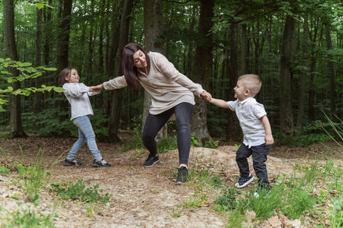 Glückliche Kinder ziehen die Mutter und haben Spaß im Wald - OSF00708
