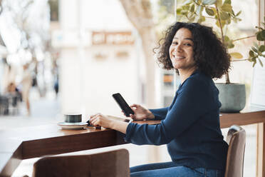 Happy woman with mobile phone in cafe - JOSEF11871