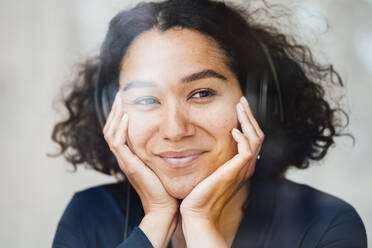 Lächelnde Frau, die über Kopfhörer Musik hört, gesehen durch Glas - JOSEF11879